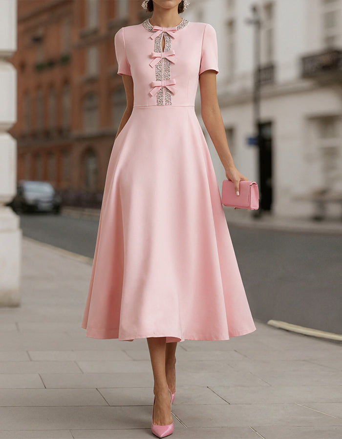 Abito midi in raso rosa con fiocco di strass che stringe la vita