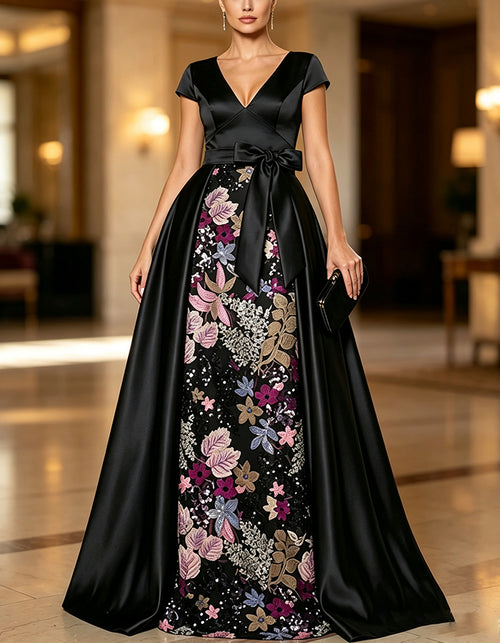 Vestido maxi de satén negro con escote en V profundo, mangas tipo capa y gran lazo en la cintura