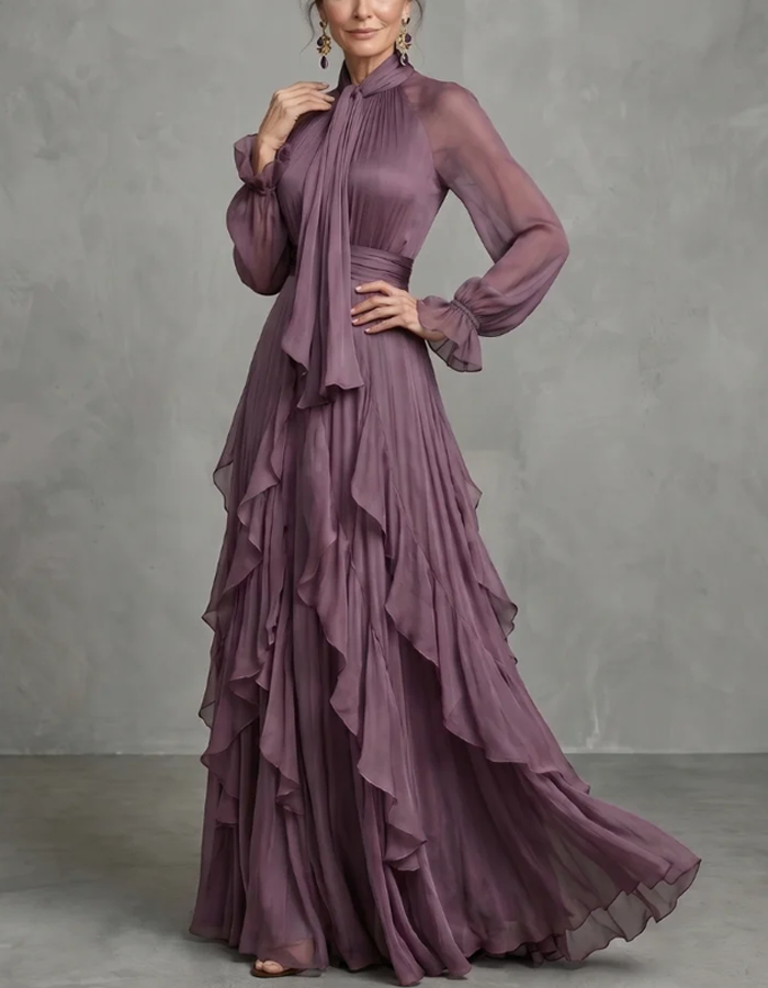 Vestido maxi lilás-claro de chiffon com laço ao pescoço, mangas compridas, folhos, corte em A e comprimento até ao chão