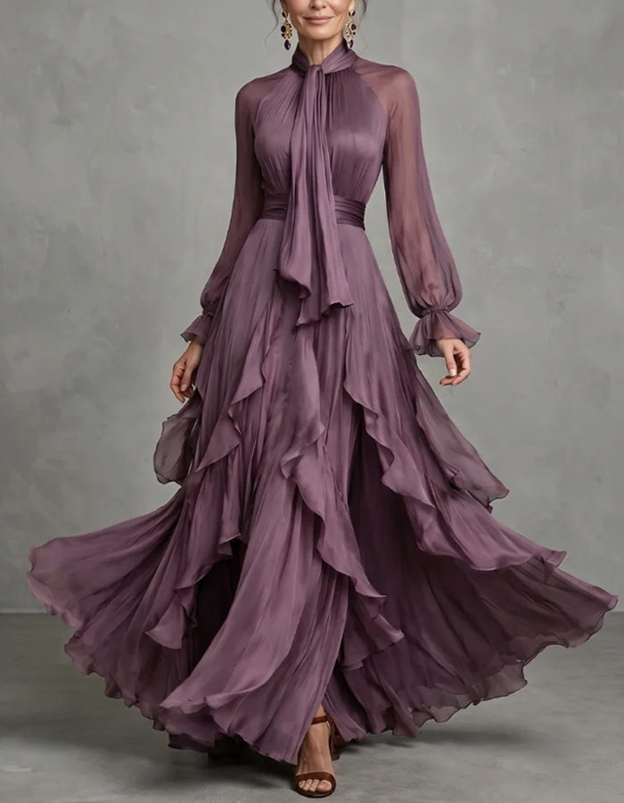 Vestido maxi lilás-claro de chiffon com laço ao pescoço, mangas compridas, folhos, corte em A e comprimento até ao chão