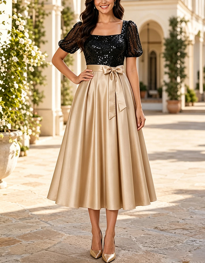 Robe midi trapèze noire et dorée en satin, à encolure carrée, manches bouffantes à sequins et nœud.