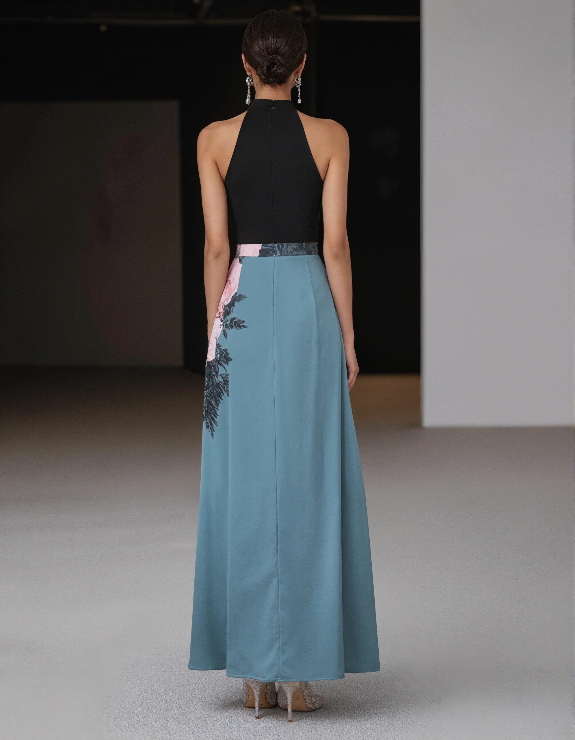 Elegante vestido de satén negro y verde azulado con detalle floral en la cintura y abertura delantera