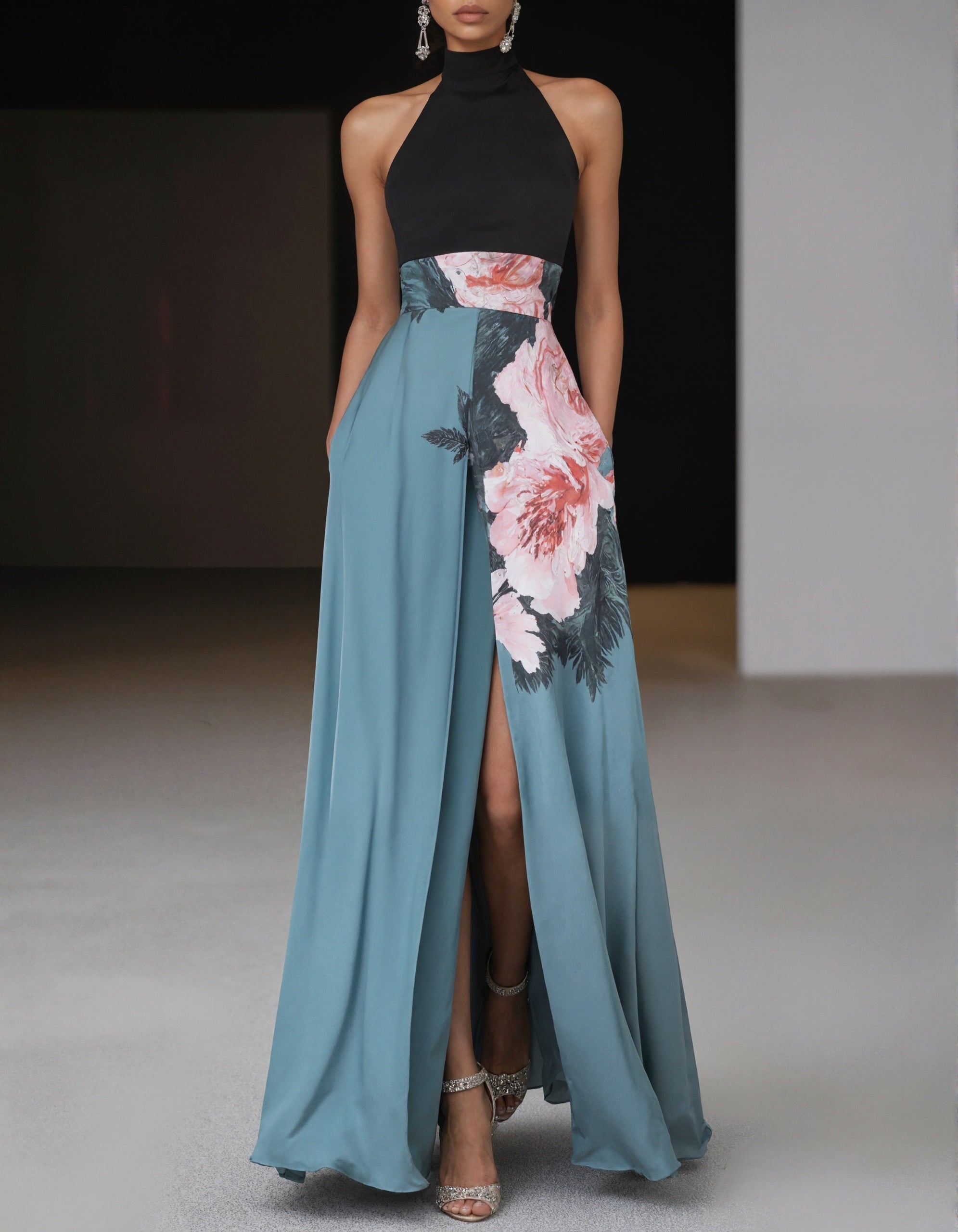 Elegante vestido de satén negro y verde azulado con detalle floral en la cintura y abertura delantera